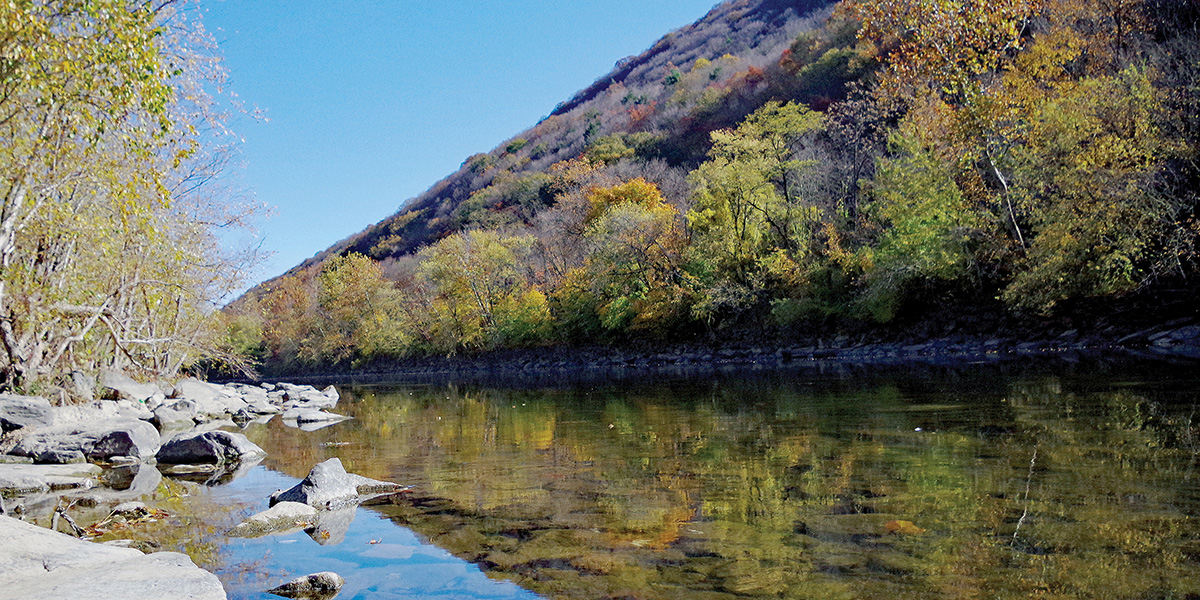 Scenic Juniata River with colorful fall forestry pictured along the stream