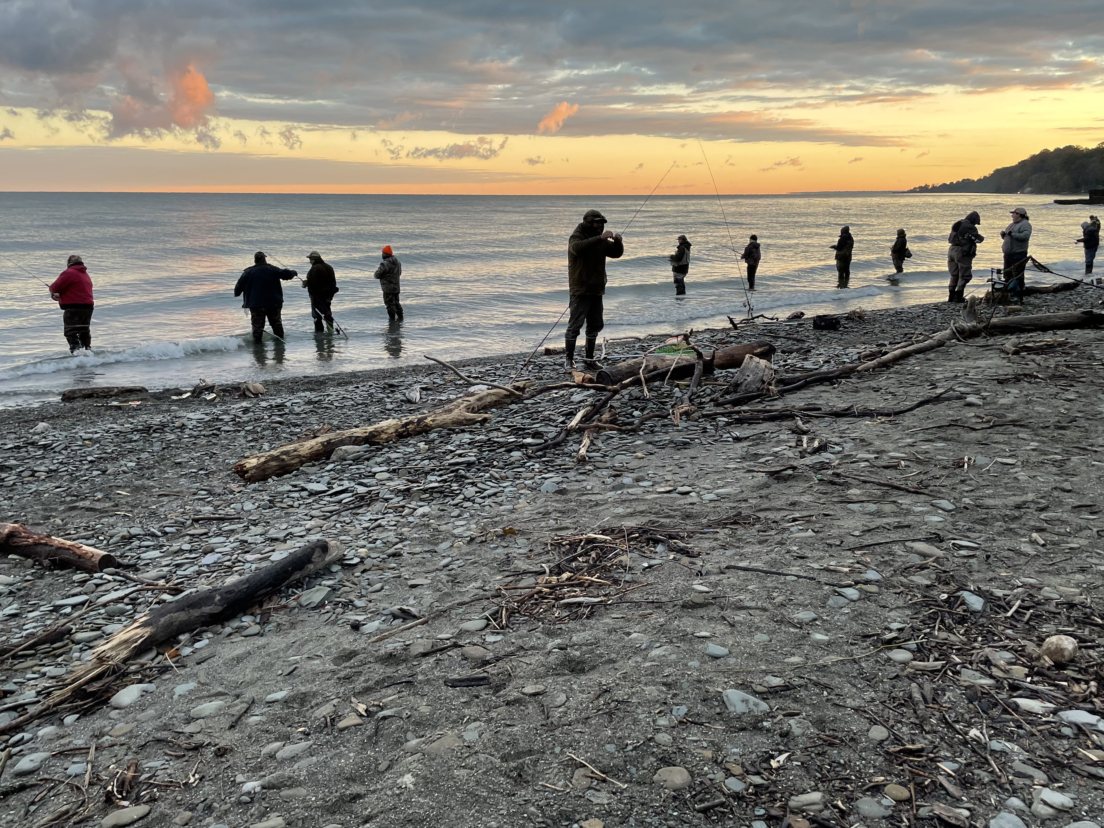 A group of anglers lined up along the Lake Erie shoreline fishing for steelhead 