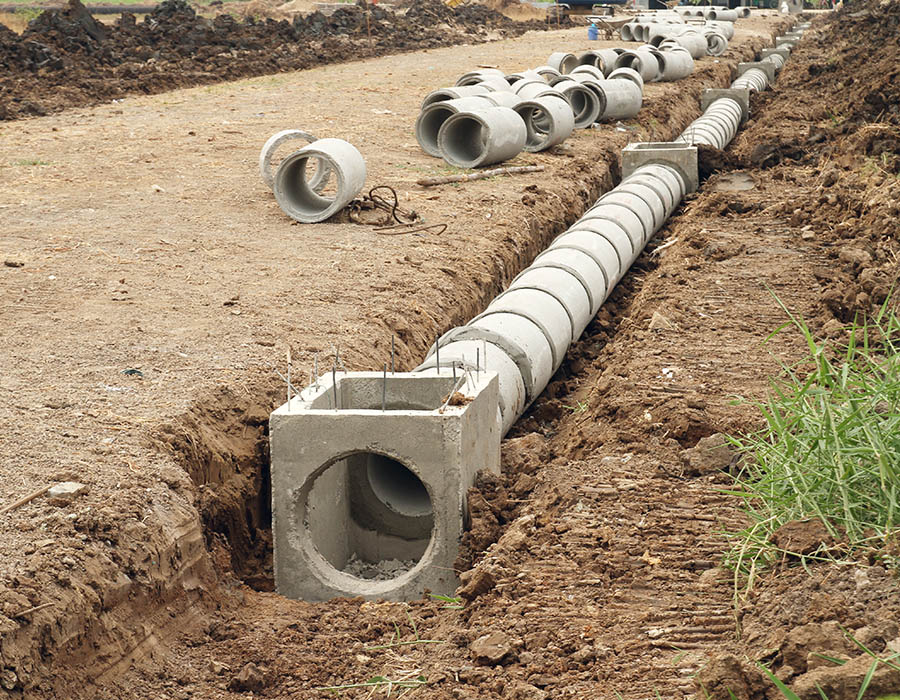A dirt trench with piping being laid
