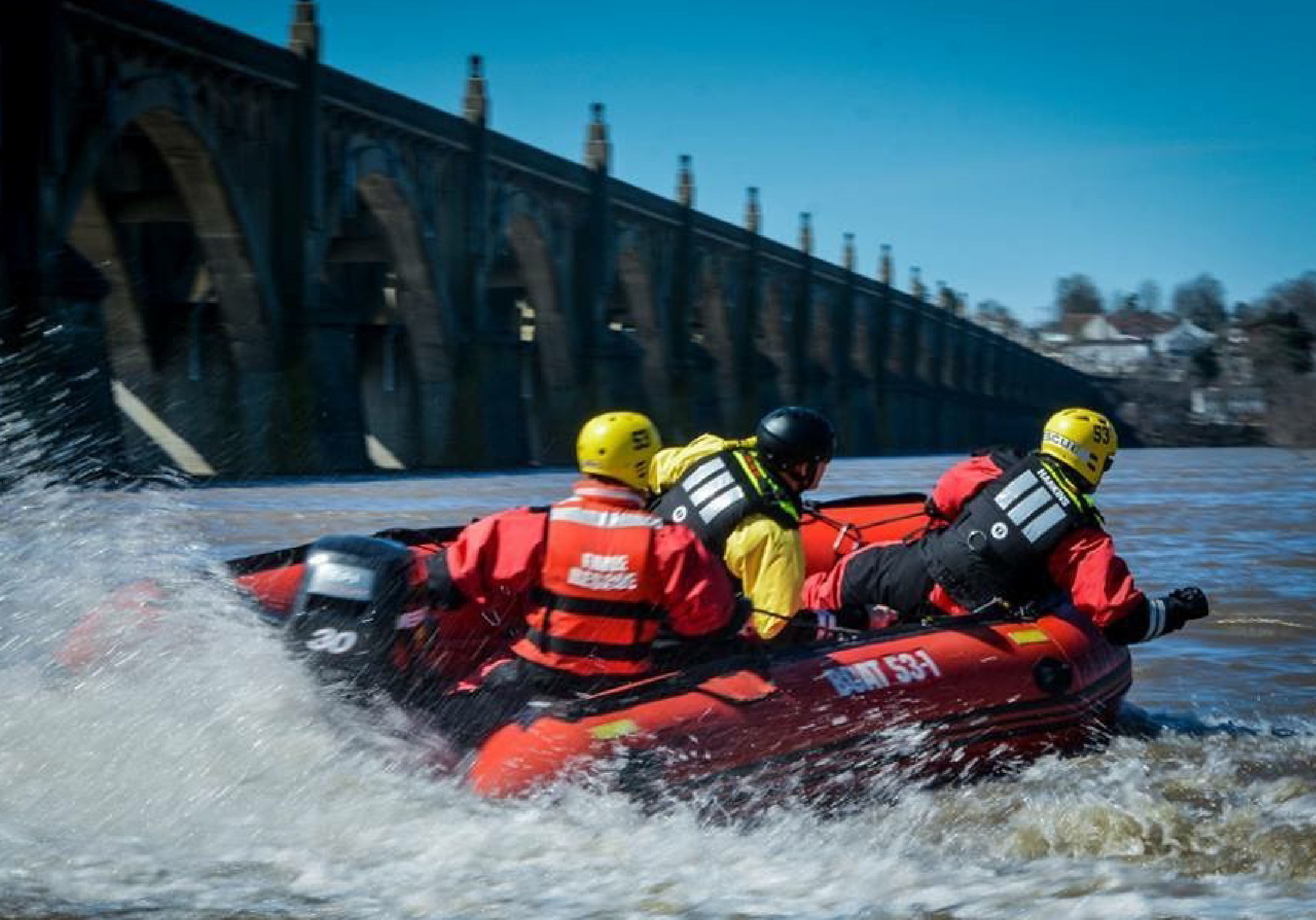 A swiftwater rescue team maneuvers through choppy water in a raft.