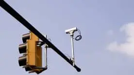 A silver traffic data collection device used to collect Automated Traffic Signal Performance Measures is mounted next to a traffic light. 