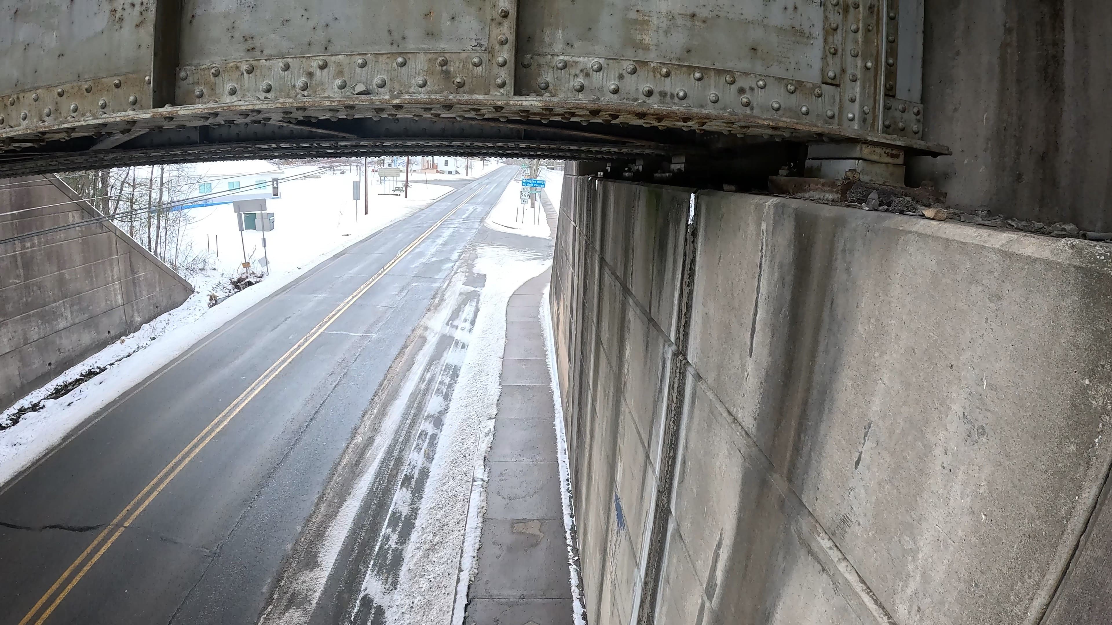 An image taken with a GoPro of the underside of a bridge over a two-lane road.