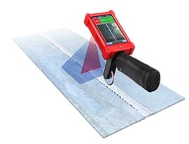 A scanner encased in a red protective case with a black handle scans a piece of metal.