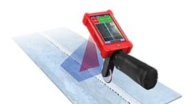A scanner encased in a red protective case with a black handle scans a piece of metal.