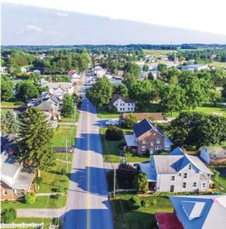 An aerial image of a two-lane roadway lined with house and trees on either side.