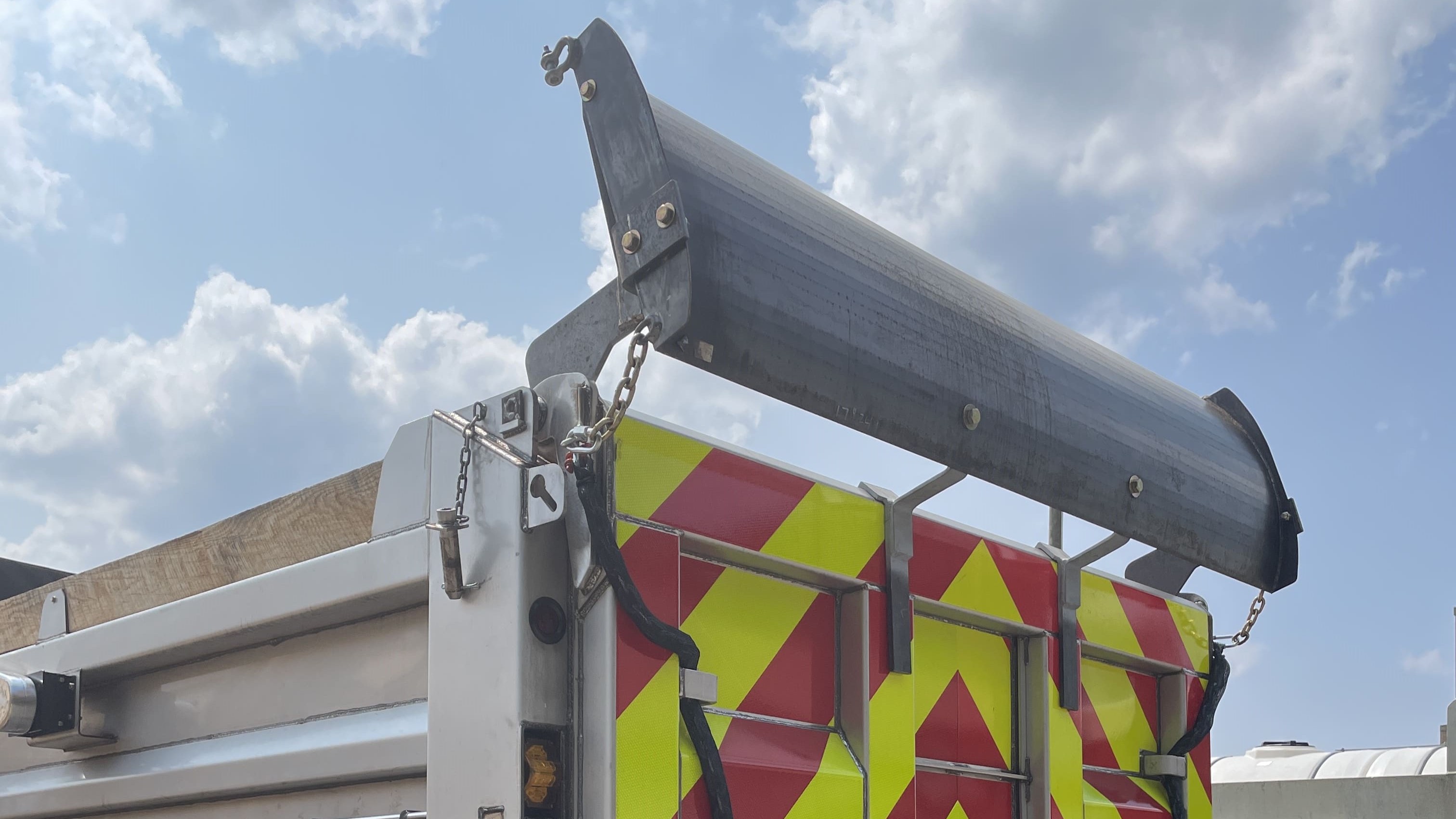 An image of a yellow PennDOT plow truck with a barrier mounted to the top to protect the truck from buildup and keep it clean. 