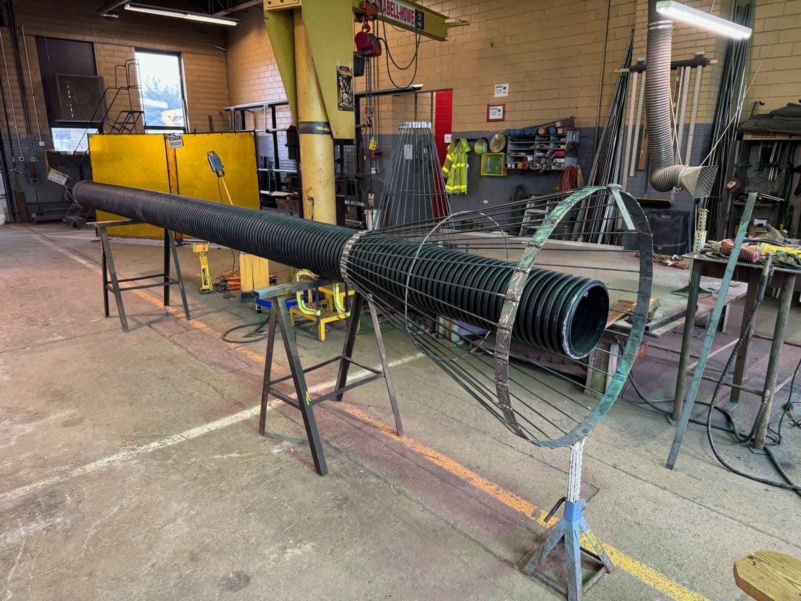 A cylindrical, metal cage with corrugated pipe running through the top of the cage, which sits atop workhorses. 