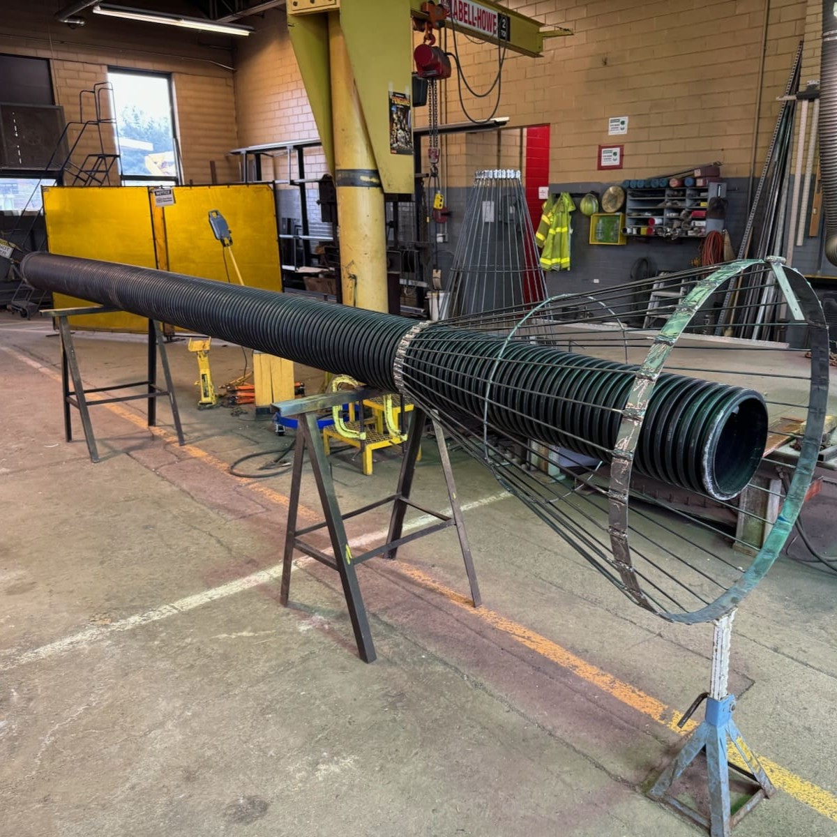 A cylindrical, metal cage with corrugated pipe running through the top of the cage, which sits atop workhorses.