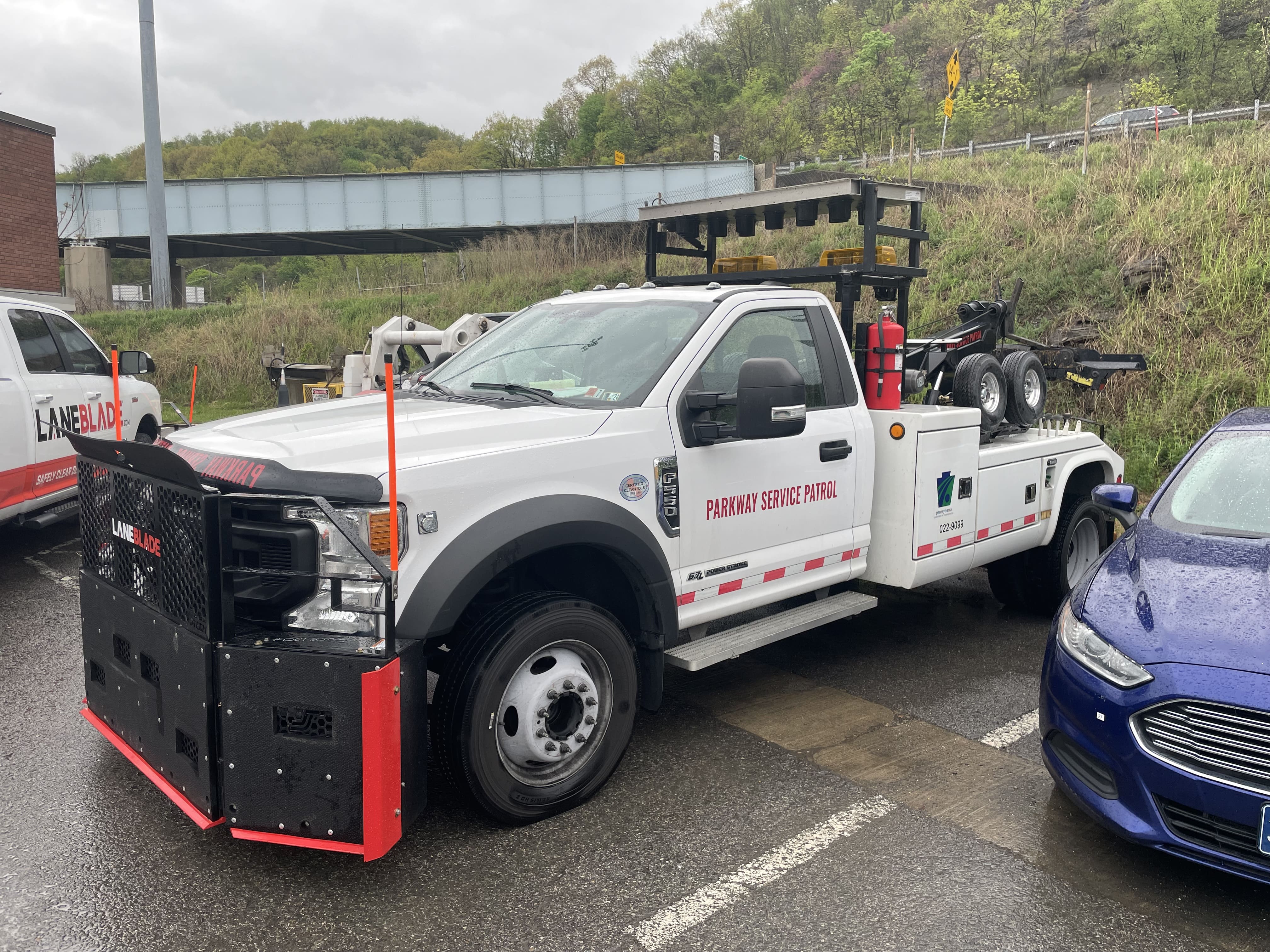 A sideview image of a white PennDOT pick-up truck with a large black metal bumper with red trim mounted to the front.