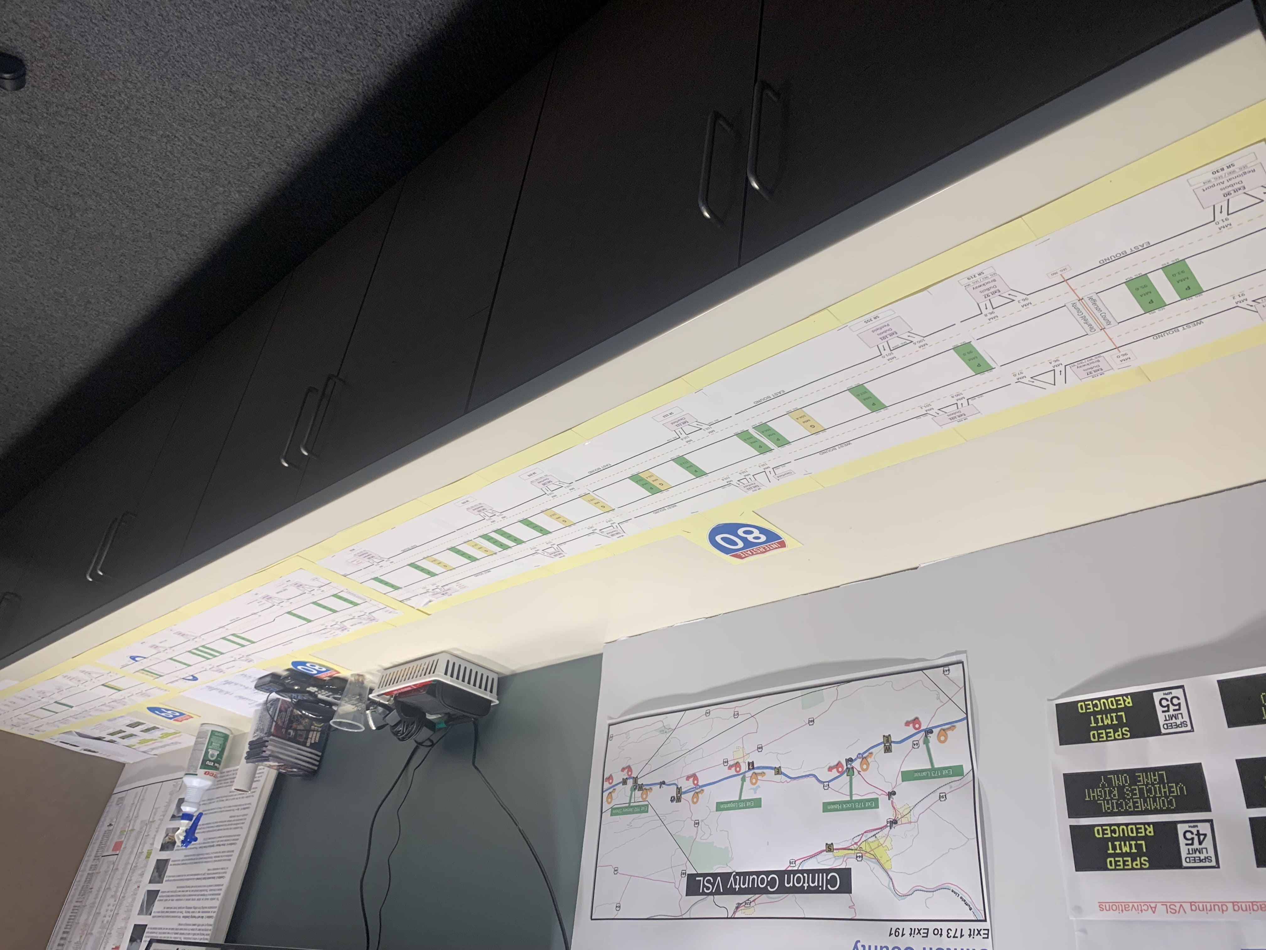 A long piece of paper showing an interstate and its mile markers and crossover points is laid out on a table.