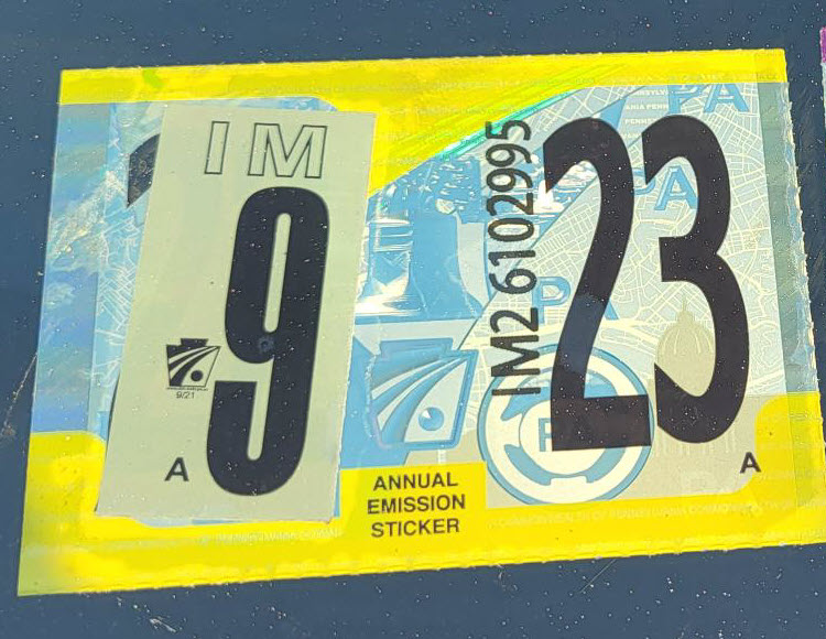 An image of a yellow annual emissions inspection sticker on a car.