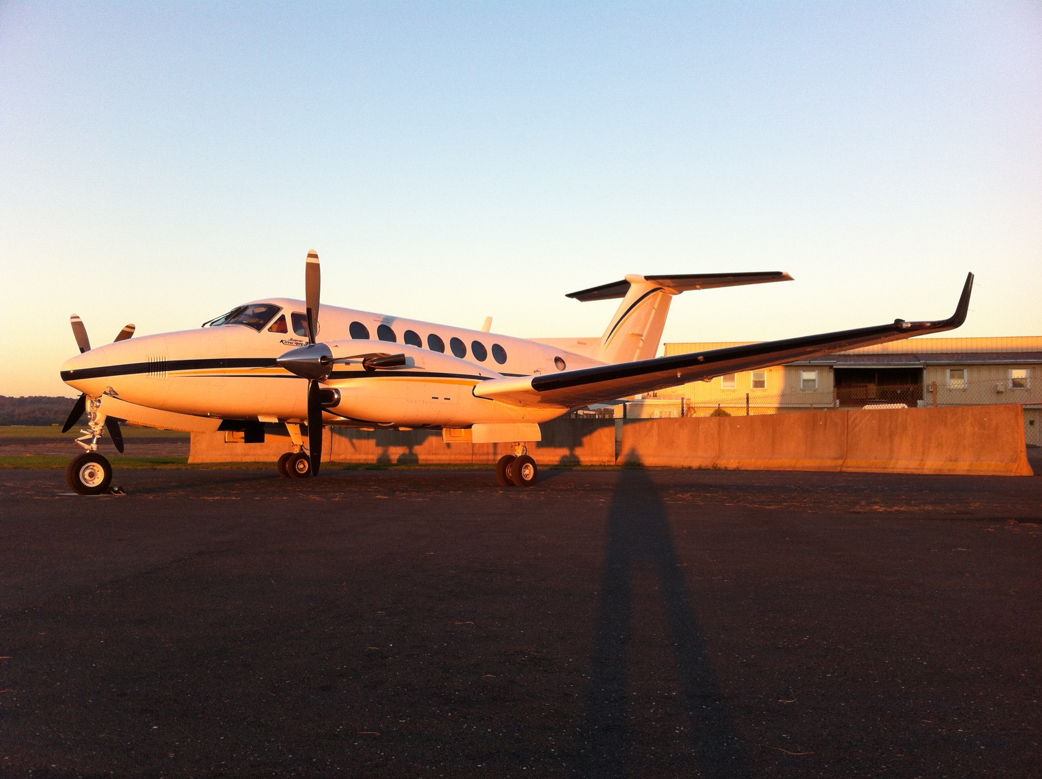 An image of a small plane sitting on an airport's tarmac at sunset
