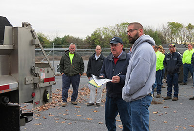 Instructor and student discussing winter maintenance vehilce while other students stand around to listen.
