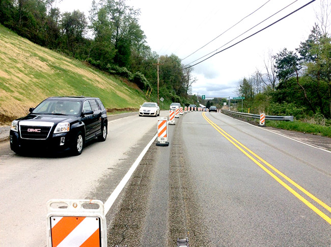 Cars restricted to one lane with safety markers on a road.