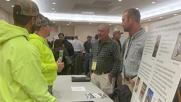 couple of regional innovation day attendees talking to a person at the booth table
