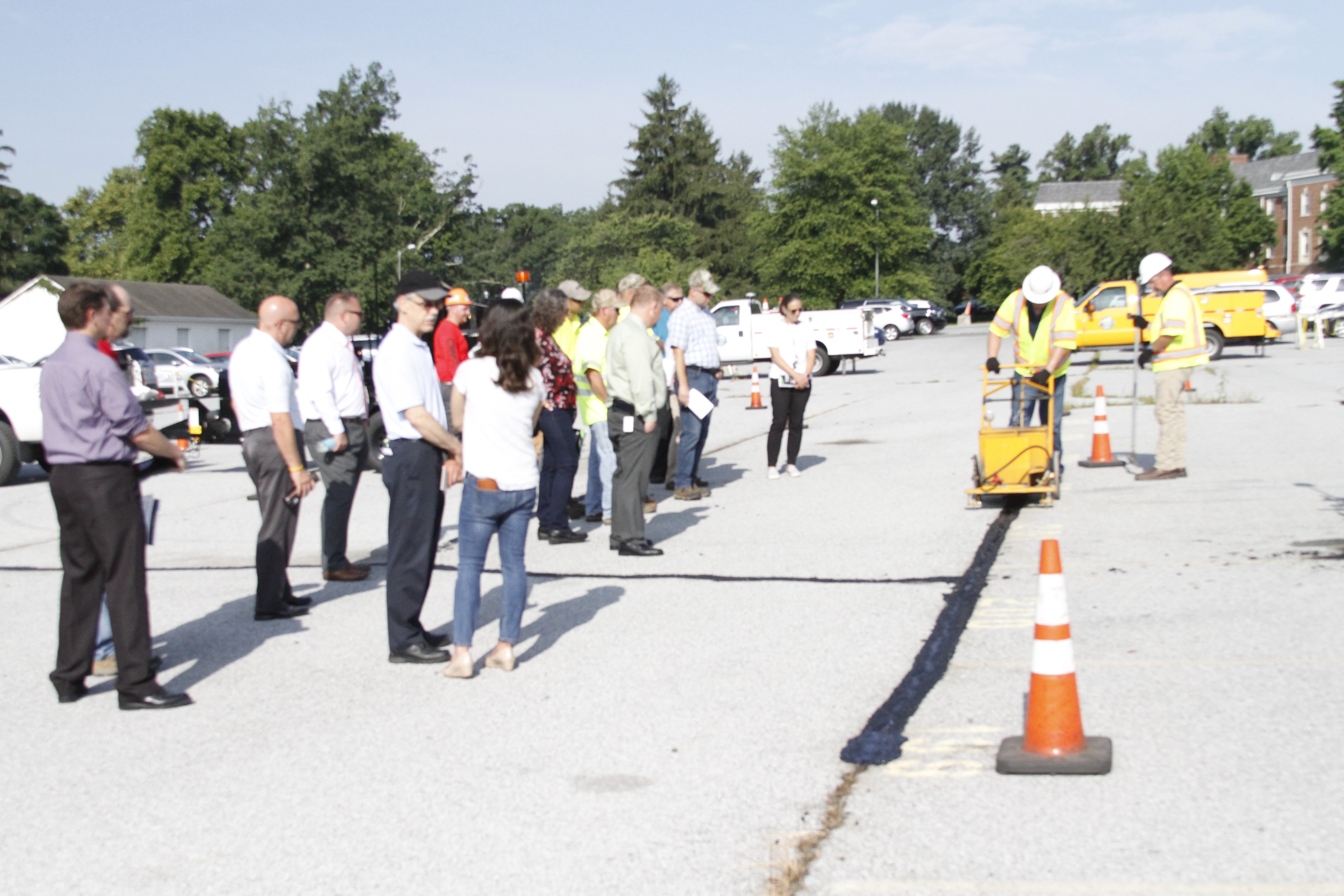 Hot Pour Mastics participants watching vendor apply product to parking lot. 