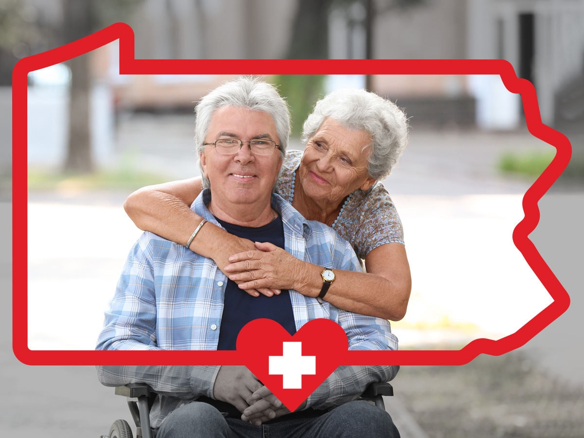 Senior woman hugging senior man in wheelchair inside the PA state frame.