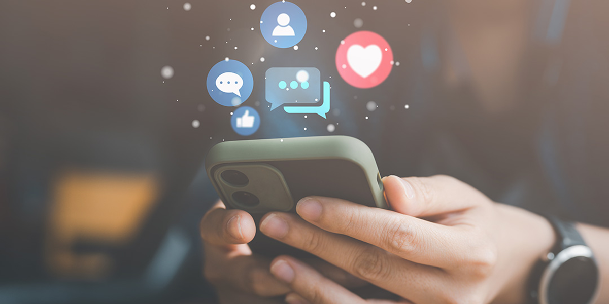 Hand holding a phone with social media icons above. 